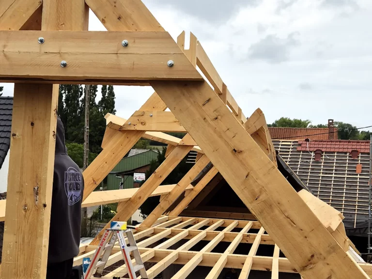 Ferme de charpente en bois massif assemblée, vue depuis le plancher du chantier.