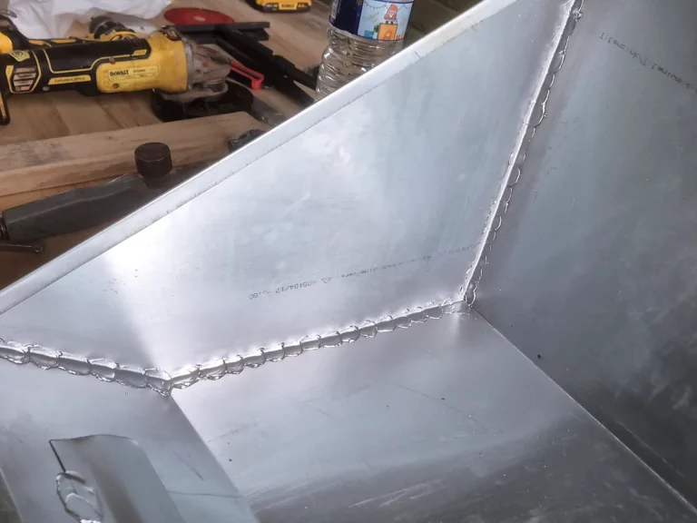Chéneau en zinc façonné et soudé sur l'établi de l'atelier de zinguerie, outillage à l'arrière.