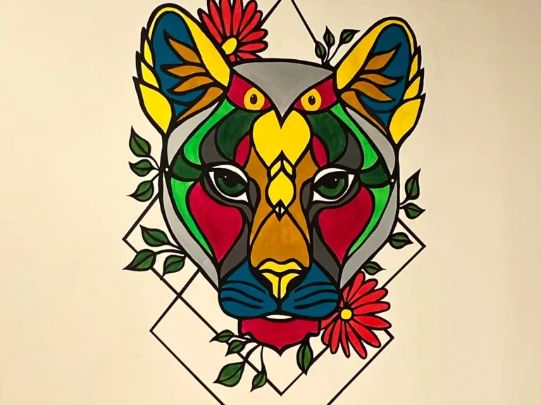 Fresque murale peinte à la main représentant une tête de félin graphique multicolore entourée de fleurs et de feuillage.