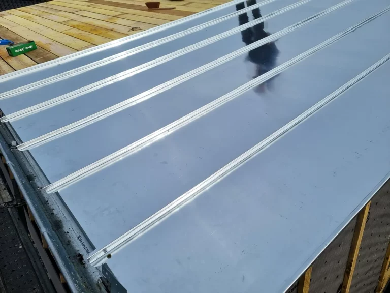 Gros plan sur les joints debout d'une couverture en zinc neuve et sur sa planche de rive.
