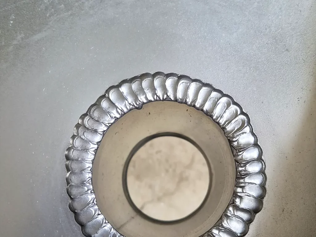Naissance de descente d'eau pluviale soudée au fond d'un chéneau en zinc, soudure régulière sur tout le pourtour.