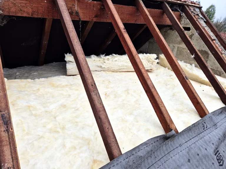 Nappe continue de laine minérale sur le plancher d'un comble perdu, vue depuis la toiture découverte.