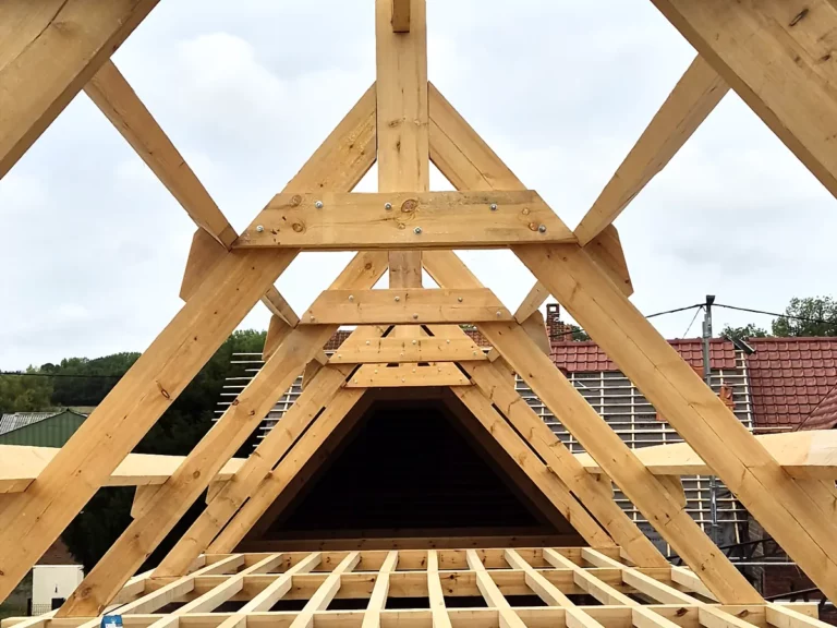 Contre-plongée sur le poinçon et l'entrait d'une ferme de charpente neuve en bois.
