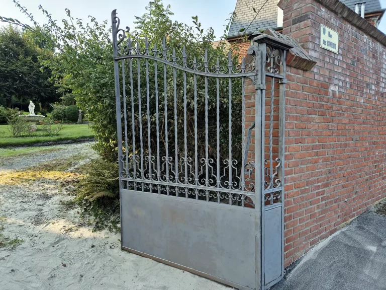 Portail en fer forgé décapé à l'aérogommage, acier remis à nu avant peinture, à l'entrée d'une propriété.