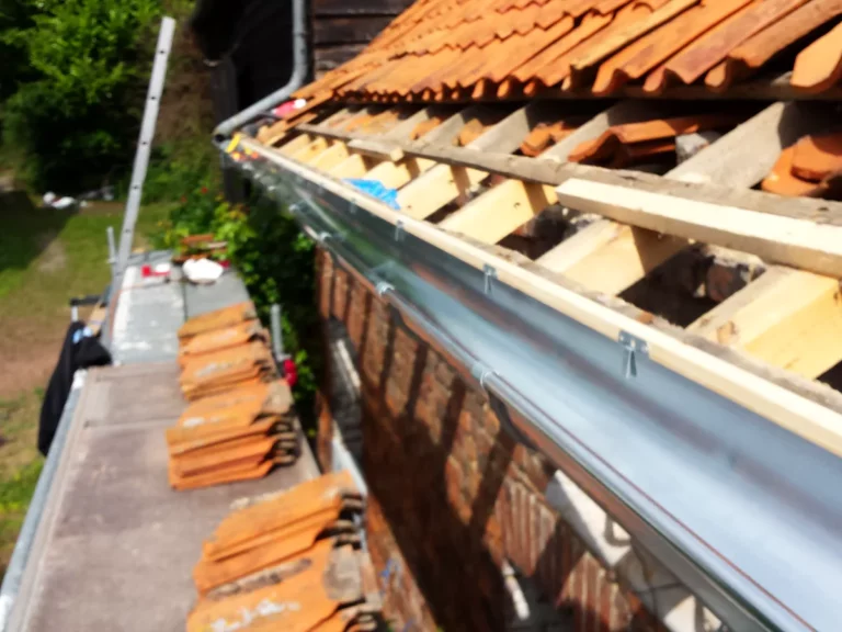 Gouttière en zinc posée à l'égout d'un toit en rénovation, le long des chevrons et liteaux neufs.