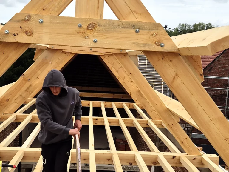 Pose des solives et de la ferme de pignon d'une charpente neuve sur un chantier de rénovation.