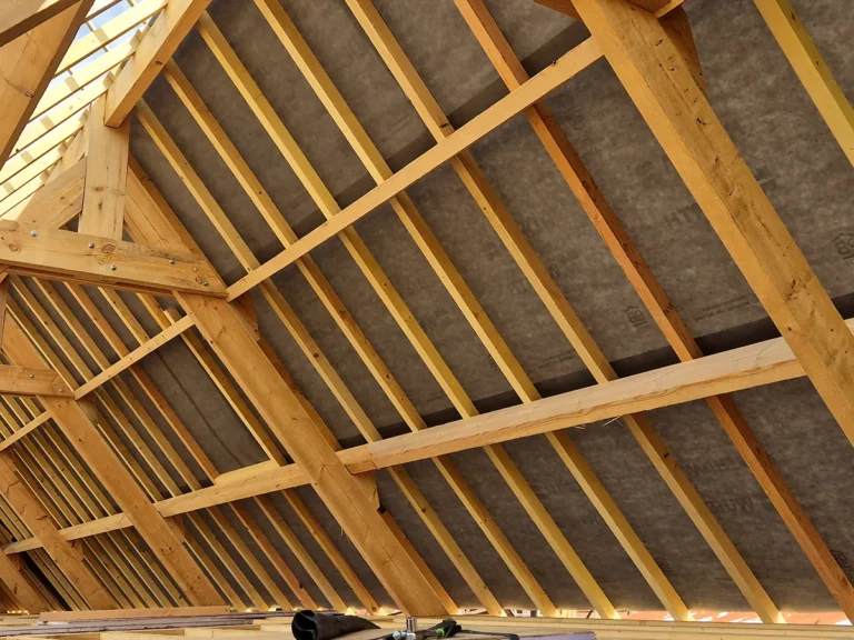 Rampants avec chevrons neufs et panneaux de sous-toiture vus depuis l'intérieur d'un comble.