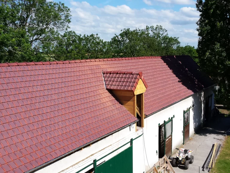 Toiture de corps de ferme entièrement refaite en tuiles, avec une lucarne habillée de bois neuf.