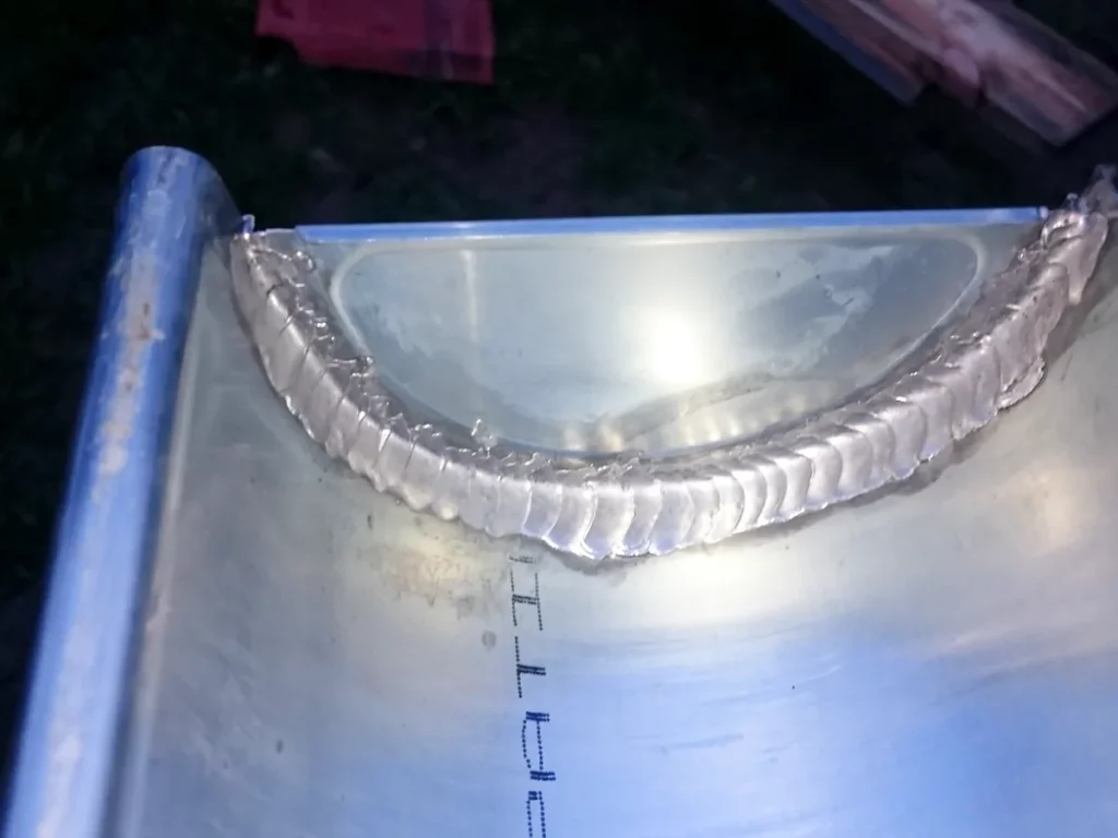 Cordon de soudure sur la cuvette d'un chéneau en zinc assemblé en atelier, tracés de façonnage encore visibles.
